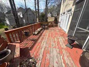 Worn red-painted deck boards with heavy peeling and cracking before deck refinishing on second-story addition — Marietta, GA