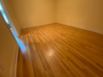 Empty basement room with cream walls and freshly installed hardwood-style flooring after water damage restoration is complete — Marietta, GA