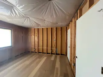 Bedroom after water damage restoration with new dark laminate flooring, fresh grey walls, and ceiling fan installed — Kennesaw, GA