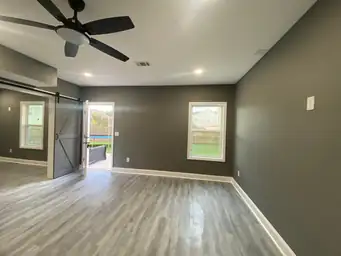 Completed basement great room with charcoal walls, gray LVP floors, sliding barn door open to backyard patio — Metro Atlanta, GA