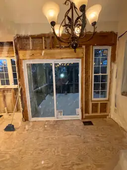 Dining area wall framing — new sliding glass door rough-opened in exterior wall, chandelier retained during kitchen renovation — Powder Springs, GA