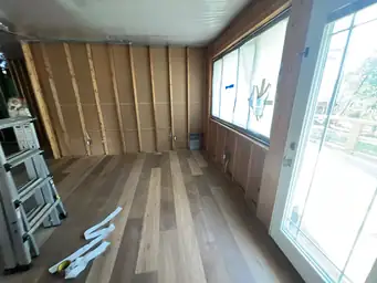 Sunroom during water intrusion remediation with drywall-stripped walls, brown sheathing, new hardwood, and poly ceiling barrier — Kennesaw, GA
