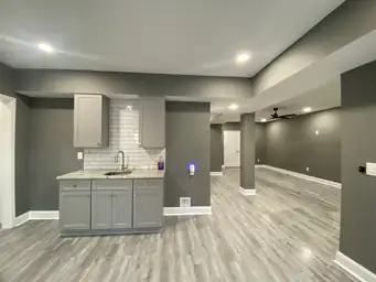 Finished basement wet bar with gray shaker cabinets, subway tile backsplash, granite countertop, and open living area — Metro Atlanta, GA