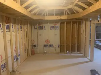Open stud wall framing with 84 Lumber wrap on OSB sheathing inside basement addition build-out — Atlanta, GA