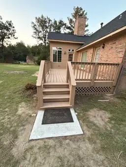 New pressure-treated lumber deck stairs and railing during deck installation with freshly poured concrete landing pad — Marietta, GA