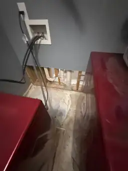 Laundry room wall opened during water damage restoration exposing wood studs and white PVC supply lines — Smyrna, GA