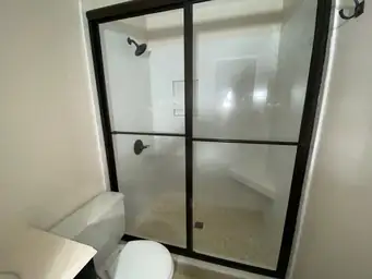 Renovated bathroom after storm damage repair with white subway tile walls, black matte fixtures, and glass enclosure — Kennesaw, GA