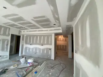 Basement finishing with drywall mud on coffered ceiling and walls, compound bucket and taping tools on floor — Metro Atlanta, GA