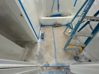 Bathroom tile work in progress with blue tape protection, plastic sheeting, and mortar floor prep during remodel — Marietta, GA