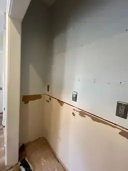 Kitchen wall after cabinet removal — countertop area stripped to backerboard, electrical outlets exposed during demo — Powder Springs, GA