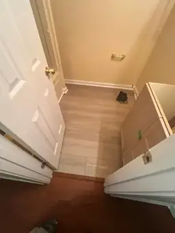 View of a small room under renovation with new wooden flooring and an unpainted cabinet — serving Dallas, GA.