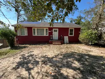 Front exterior of storm-damaged home with cleared yard and replacement door panels staged on porch before repair — Acworth, GA