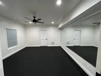 Renovated flex room with full-wall mirror, LED cove lighting, black ceiling, and polished epoxy floor — Metro Atlanta, GA