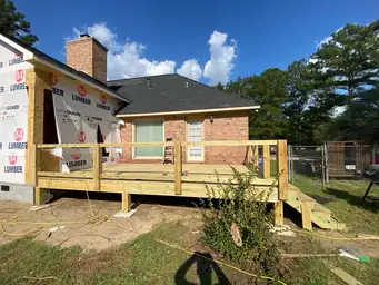 Rear exterior of brick home showing old deteriorated red painted deck and bare yard before home addition project — Marietta, GA