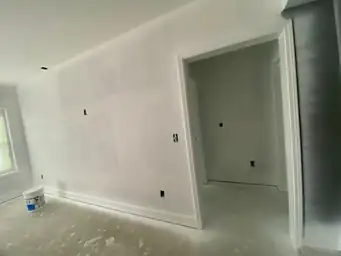 Basement bedroom finish phase with smooth primed drywall walls, white door casing trim, and closet opening framed — Metro Atlanta, GA