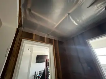 Bedroom ceiling covered in plastic tarping after storm damage with stripped wood stud walls and door frame exposed — Acworth, GA