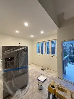 Kitchen renovation during construction — new recessed lighting, refrigerator wrapped, wide windows roughed in, deck door opening — Powder Springs, GA