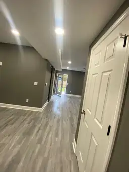 Finished basement hallway toward backyard exit door, gray LVP flooring, charcoal walls, and recessed can lighting — Metro Atlanta, GA