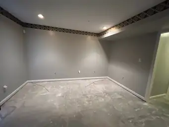A room with gray walls, missing baseboards, and an unfinished floor, during construction — serving Dallas, GA.