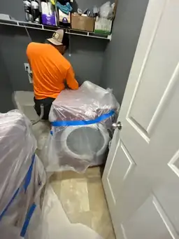 Technician wrapping appliances in plastic during interior flooding damage containment in grey laundry room — Smyrna, GA