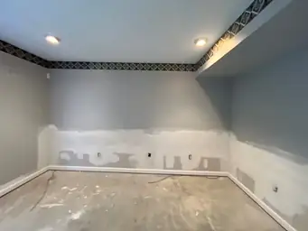 Room under construction with drywall compound on walls, recessed lights, and bare floor — serving Dallas, GA.