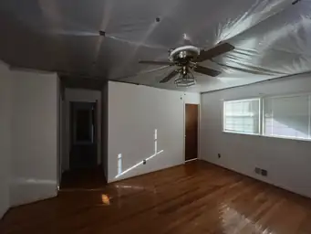 Wide living room with plastic sheeting sagging on ceiling and hardwood floors before storm water damage cleanup — Marietta, GA